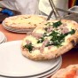 Fresh wood oven baked pizza slides onto a plate in a pizza restaurant in Sorrento Italy
