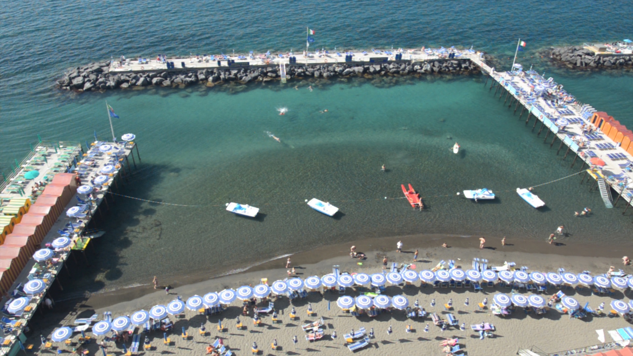 A nice sandy beach with a pier on either side and one of the piers leading to a breakwater in Sorrento Itlay