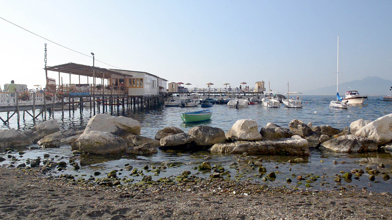 A pier and marina stretching out to sea from a rock beach Sorrento Italy