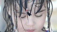 A close up of a young beach girl with intense blue eyes and wet hair with a few beach braids, looking down at the beach sand at the Iberostar Laguna Azul Beach Resort in Varadero Cuba