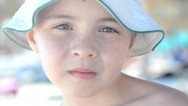 A close up of a 7 year old beach boy with intense blue eyes and bucket hat, standing on the beach looking at the camera at the Iberostar Laguna Azul Beach Resort in Varadero Cuba