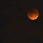 a time lapse frame of the Supermoon Lunar Eclipse of September 27 2015. at the red moon or blood moon stage, with some clouds obscuring the view.
