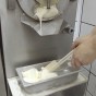 Gelato from a gelato machine starts to fill up a gelato tub a scoop at a time Sorrento Italy