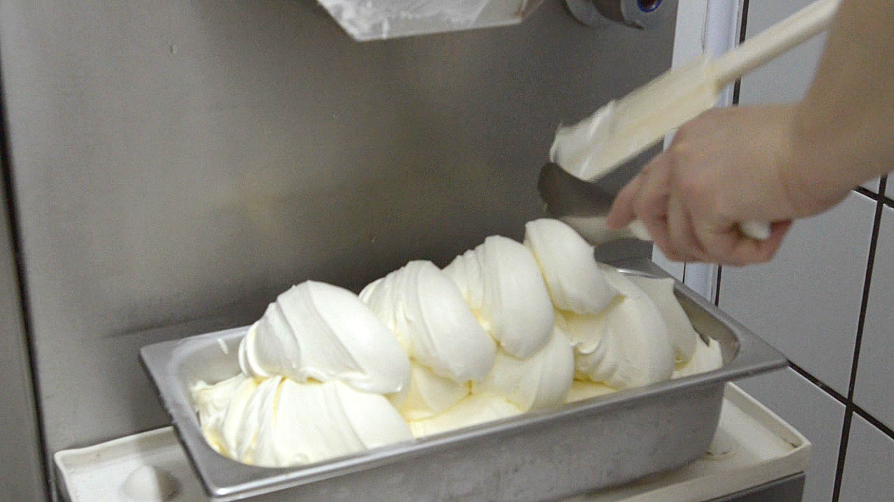 The last scoop of gelato from a gelato machine fills up a gelato tub Sorrento Italy