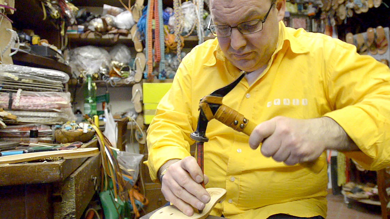 Shoe Maker in Sorrento Italy hammering a notch in the soul of a pair of Custom hand made Italian leather sandals