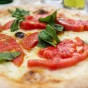 A close up of a margarita pizza fresh out of the wood oven showing the detail of the pizza crust, cheese, tomato