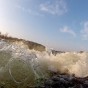 The photograph shows a close up side view of the rumbling water of the wake wave with the sky in the background.