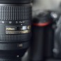 The photograph is a close up of the Nikkor AS-S 24-120 f4 zoom lens showing the number marking on the zoom collar of the lens and some of the other word marks including the Nikon word mark on the barrel of the lens. The Nikon D750 camera body is somewhat blurry in the background