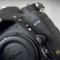 The photograph is a close up three quarter view of the Nikon D750 camera body on a slight angle while is bein lifted out of the plastic wrap the Nikon D750 camera body was packaged in. The D750 word mark on the Nikon D750 camera body is sharp and central with the Nikon word mark off to the side and slightly out of focus and the FX logo at the bottom of the Nikon D750 camera body is visable and at the bottom of the photograph.